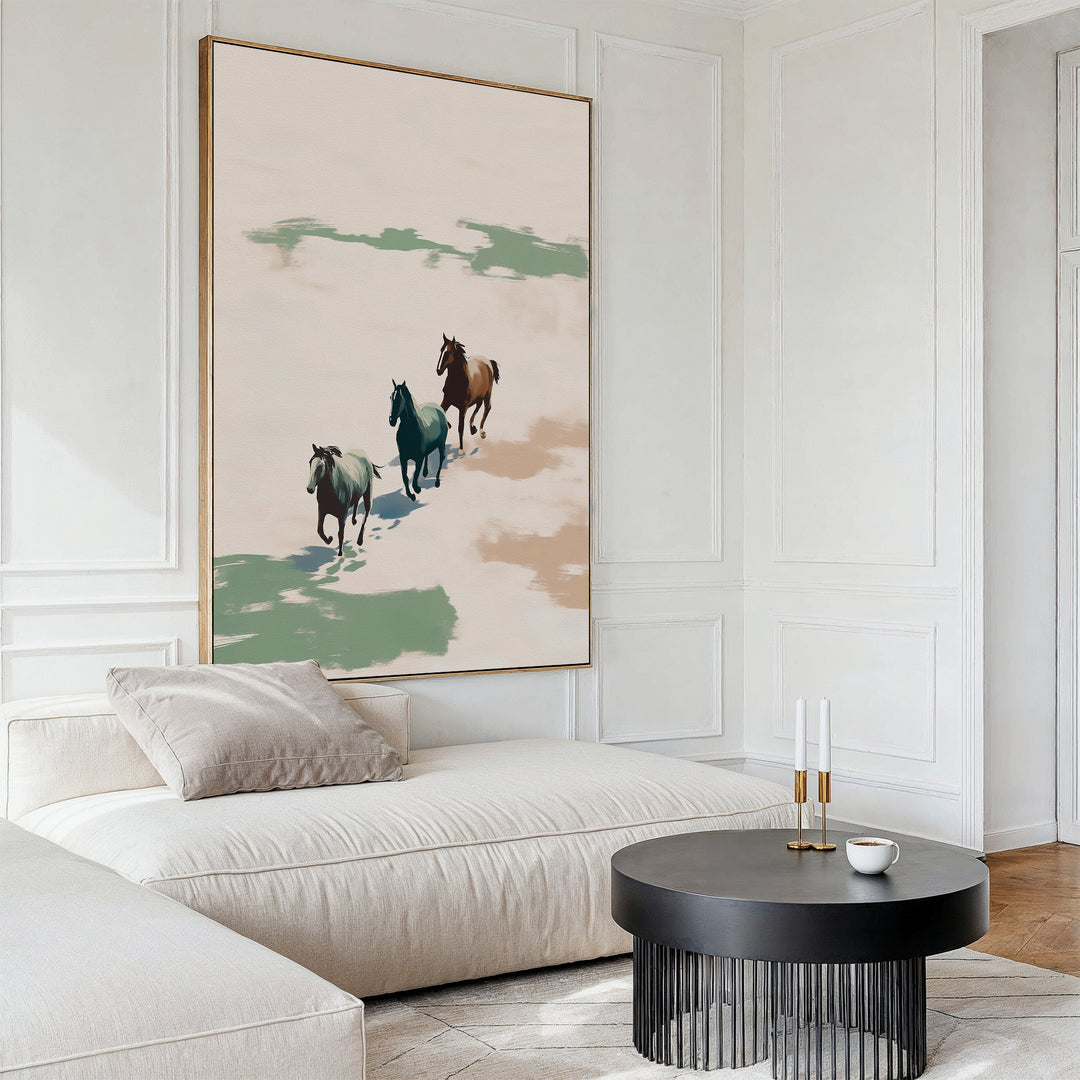 A modern living room with a light beige sectional, a round black coffee table, and the Running Free Canvas Art displaying three horses in muted green and brown tones, creating a minimalist vibe.