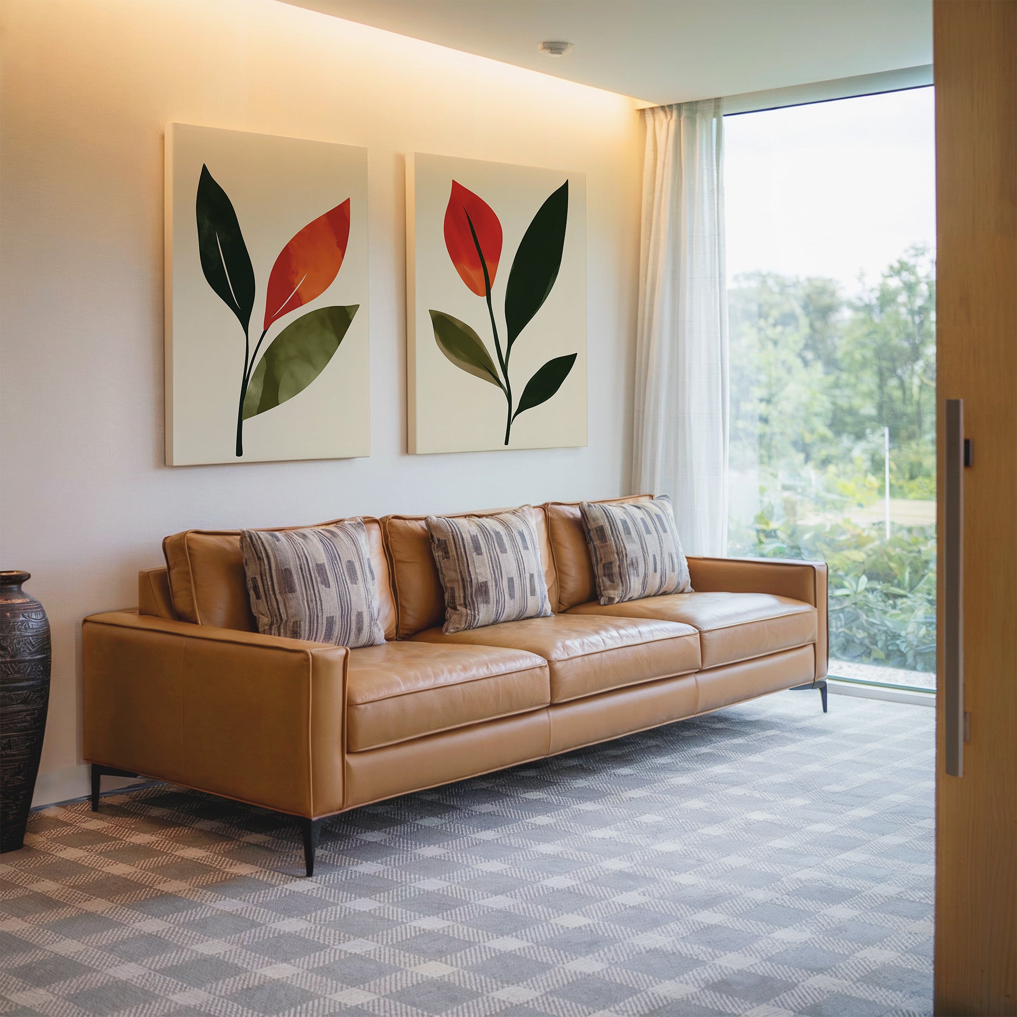A modern living room with a tan leather sofa, patterned pillows, olive green wall art, sheer curtains, patterned carpet, and a large window. The Rustic Stems Set of 2 decorative vases sit on the floor beside the sofa.