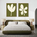 A modern bedroom featuring an olive green bed, white bedding, matching nightstands with beige lamps, and the Sage Petal Set of 2 abstract floral wall art prints with olive green backgrounds hanging above the bed.