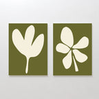 The Sage Petal Set of 2 features minimalist wall art prints with cream floral silhouettes on sage green backgrounds, each with a distinct abstract design, displayed side by side on a plain white wall.