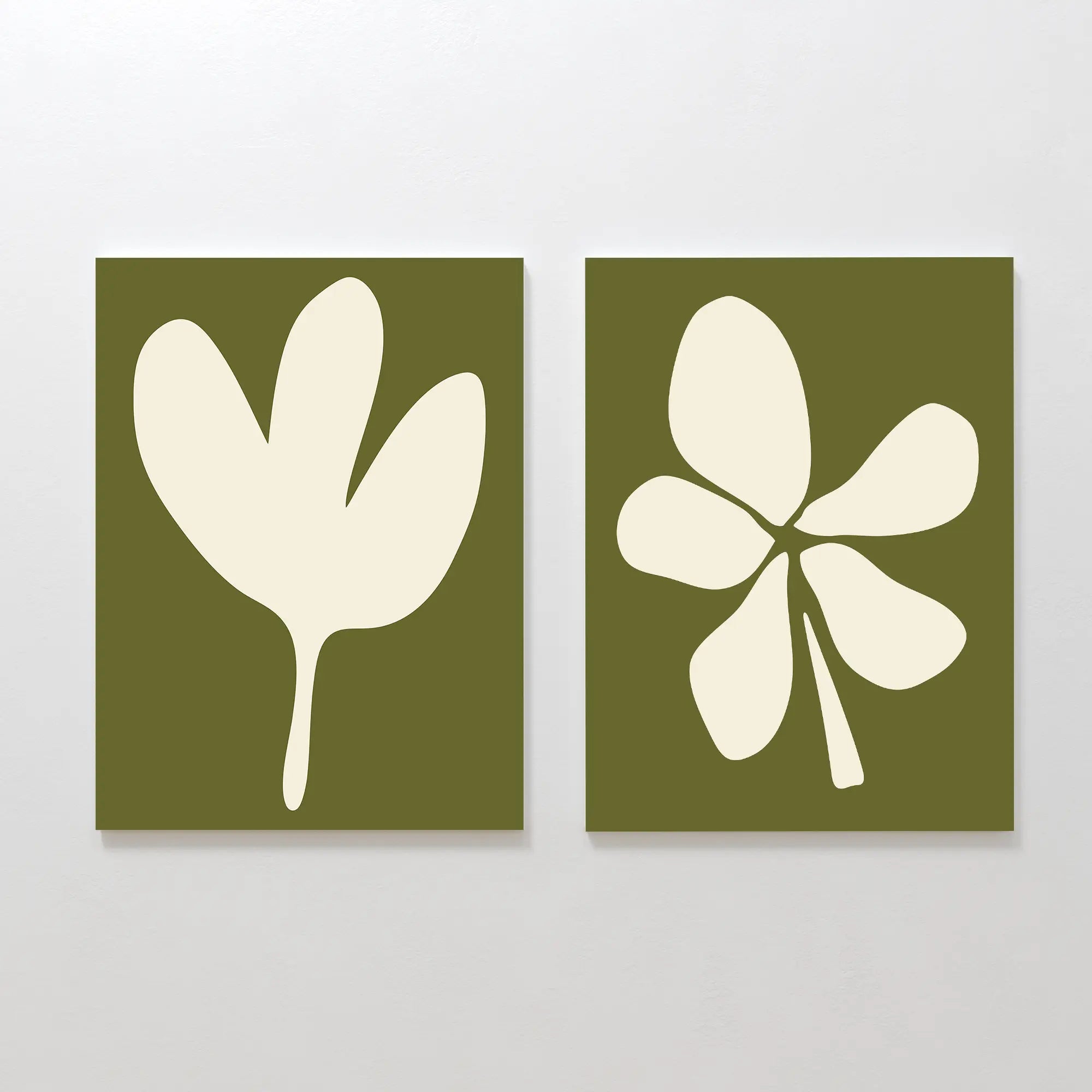 The Sage Petal Set of 2 features minimalist wall art prints with cream floral silhouettes on sage green backgrounds, each with a distinct abstract design, displayed side by side on a plain white wall.