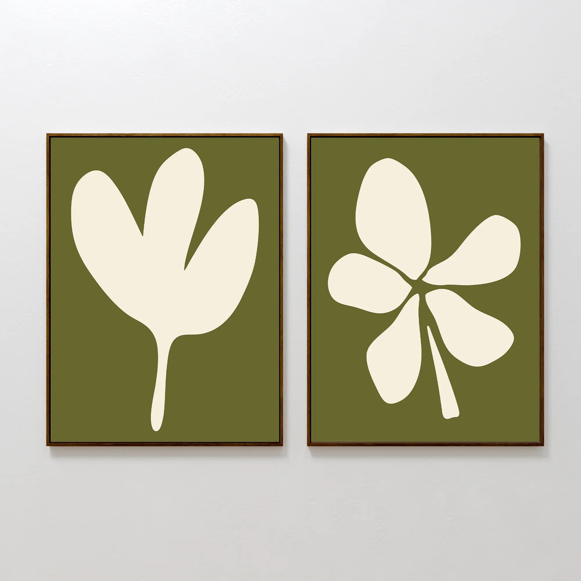 The Sage Petal Set of 2 features framed wall art prints on a white wall with cream floral silhouettes on sage green backgrounds—one print shows a three-lobed leaf, the other highlights a five-lobed leaf.