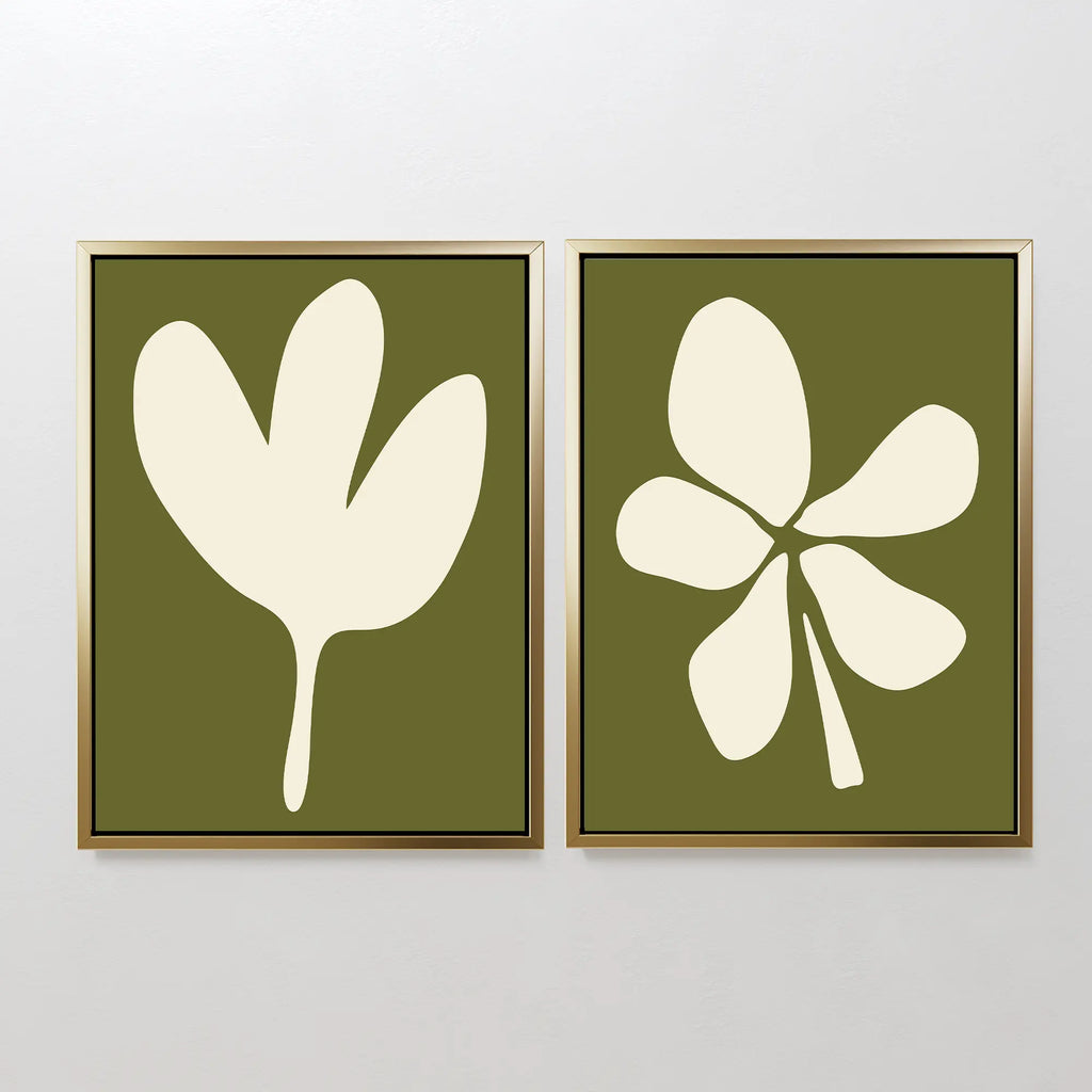 The Sage Petal Set of 2 features framed minimalist wall art prints with abstract white floral silhouettes and unique leaf designs on sage green backgrounds, displayed side by side on a light-colored wall.