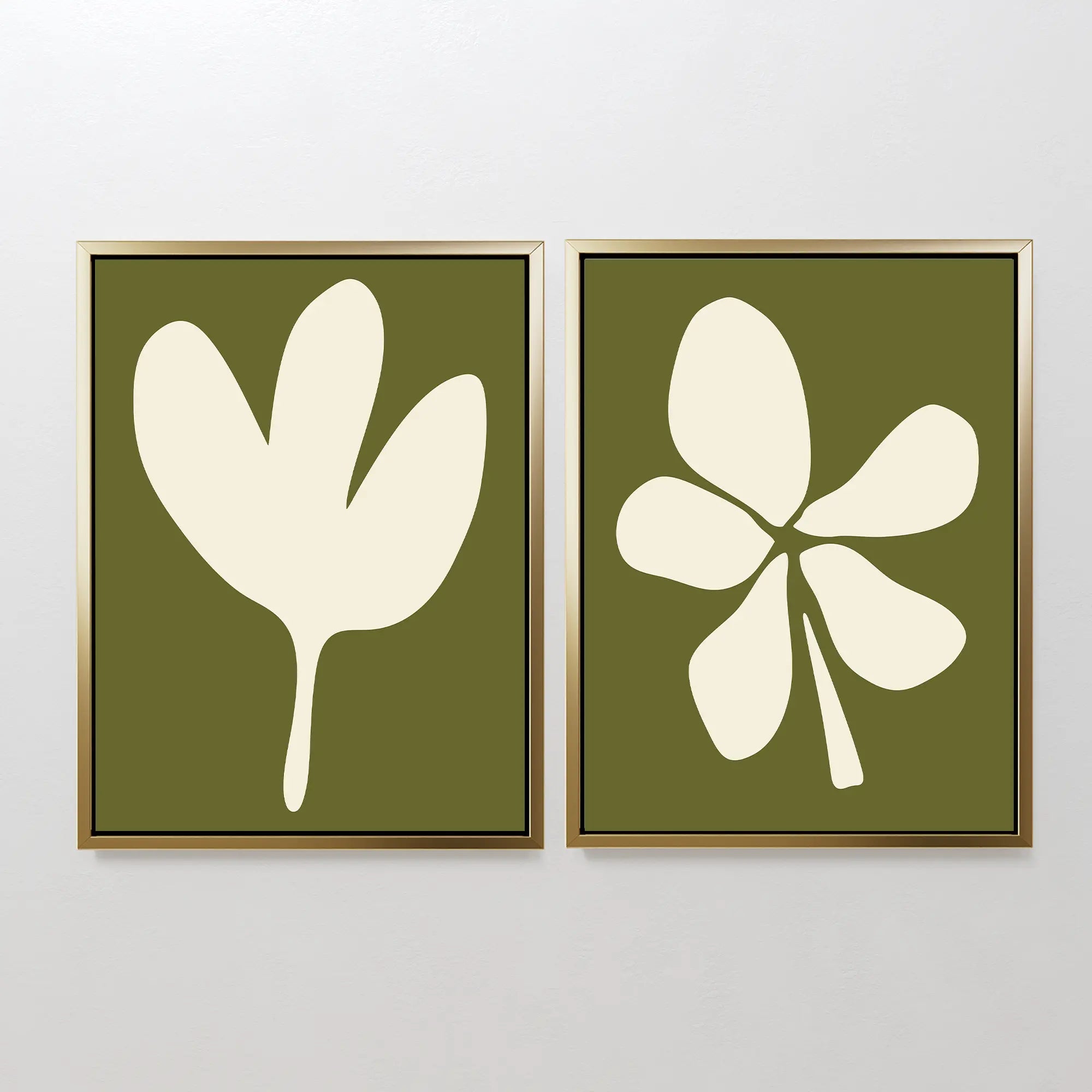 The Sage Petal Set of 2 features framed minimalist wall art prints with abstract white floral silhouettes and unique leaf designs on sage green backgrounds, displayed side by side on a light-colored wall.