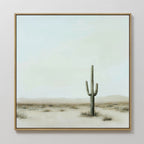 The Saguaro Whisper Canvas Art is a large framed painting showcasing a minimalist desert landscape with a central tall saguaro cactus, sparse dry grass, and a soft blue sky with light clouds.