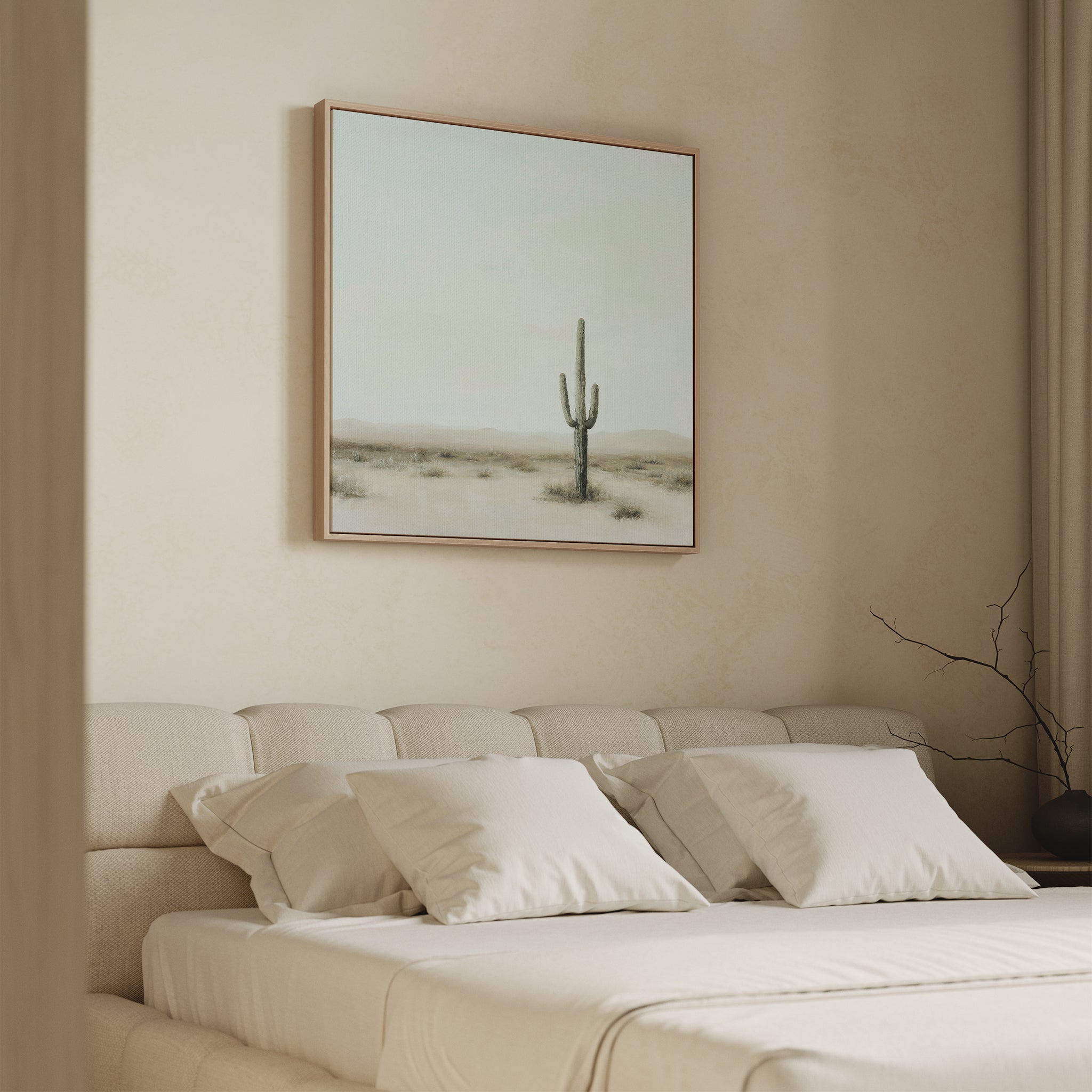 A minimalist bedroom features a beige upholstered bed with four white pillows and the Saguaro Whisper Canvas Art hanging above the headboard. Neutral tones define the room’s decor.