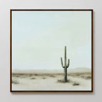 The Saguaro Whisper Canvas Art is a framed minimalist wall piece depicting a single tall saguaro cactus in a desert landscape, with soft muted tones and a pale sky, capturing serene simplicity for your space.