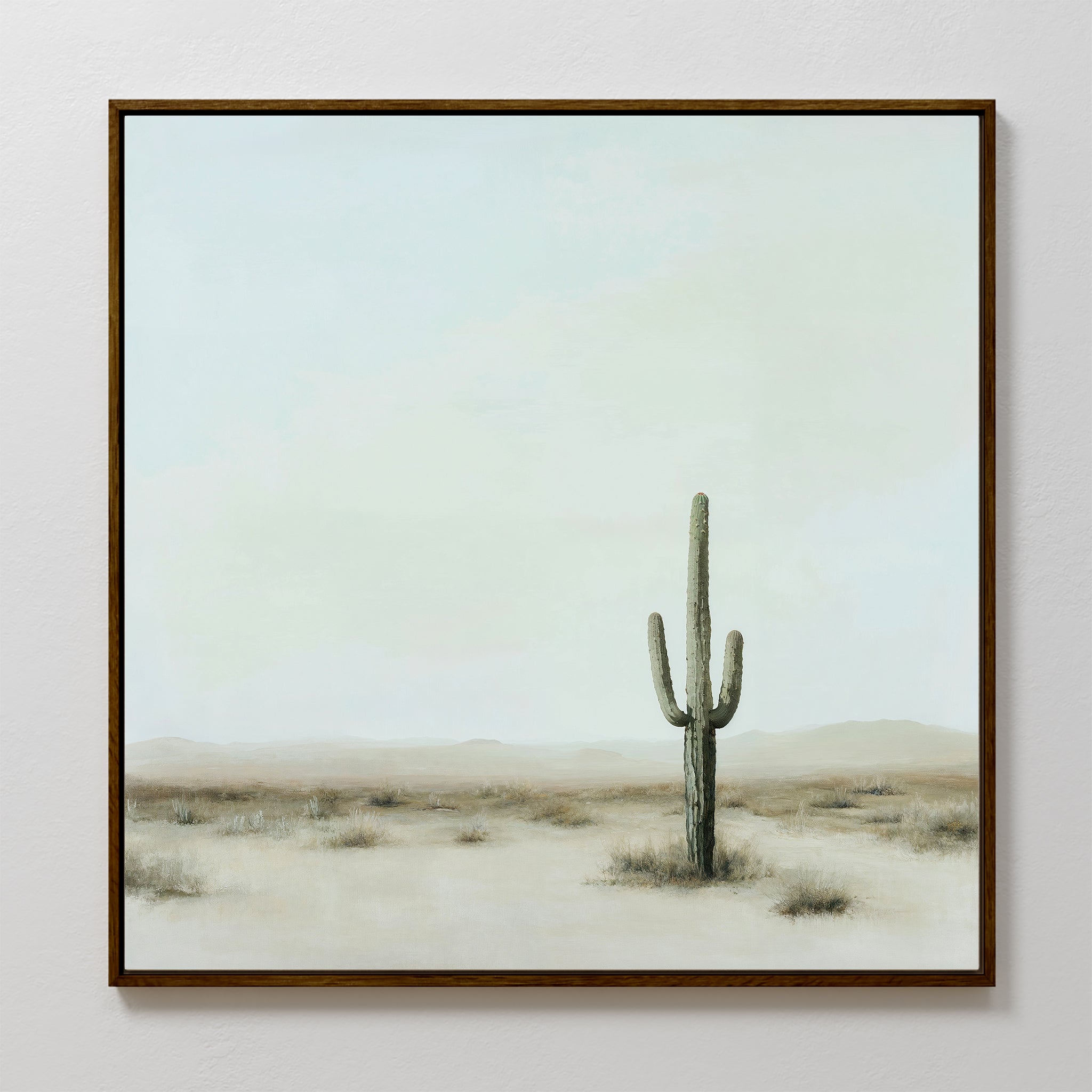 The Saguaro Whisper Canvas Art is a framed minimalist wall piece depicting a single tall saguaro cactus in a desert landscape, with soft muted tones and a pale sky, capturing serene simplicity for your space.