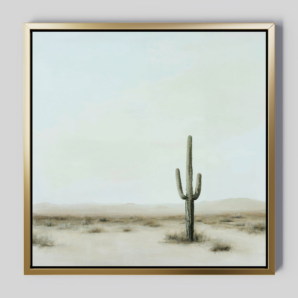 The Saguaro Whisper Canvas Art showcases a tall saguaro cactus in a serene desert landscape under a pale, cloudy sky. This minimalist wall art comes framed in gold, adding tranquil elegance to any space.