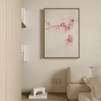 A minimalist living room corner features a light beige sofa, a small bookshelf, and the Sakura Dream Canvas Art, which displays delicate pink flowers on a white background. Neutral tones throughout create a calm, inviting atmosphere.