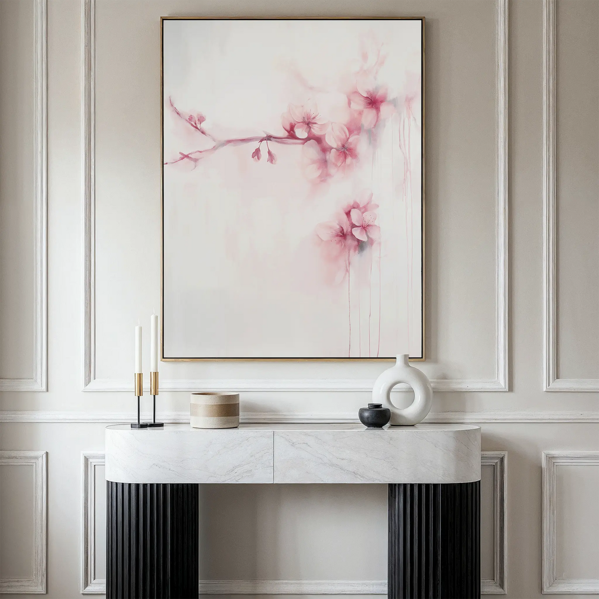 A console table with minimalist decor stands against a wall with decorative molding. Above it hangs the Sakura Dream Canvas Art, featuring delicate pink flowers on a pale background.