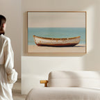 A person in white admires the Sandbound Vessel Canvas Art—a framed painting of an old white boat on a sandy beach—hanging above a light sofa in a bright, minimalist room. Ideal for adding serenity to bedroom decor.