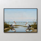 Seaside Gaze Canvas Art features two pelicans by coastal grasses and tranquil water, their reflections shining under a clear blue sky—ideal minimalist wall décor for your home.