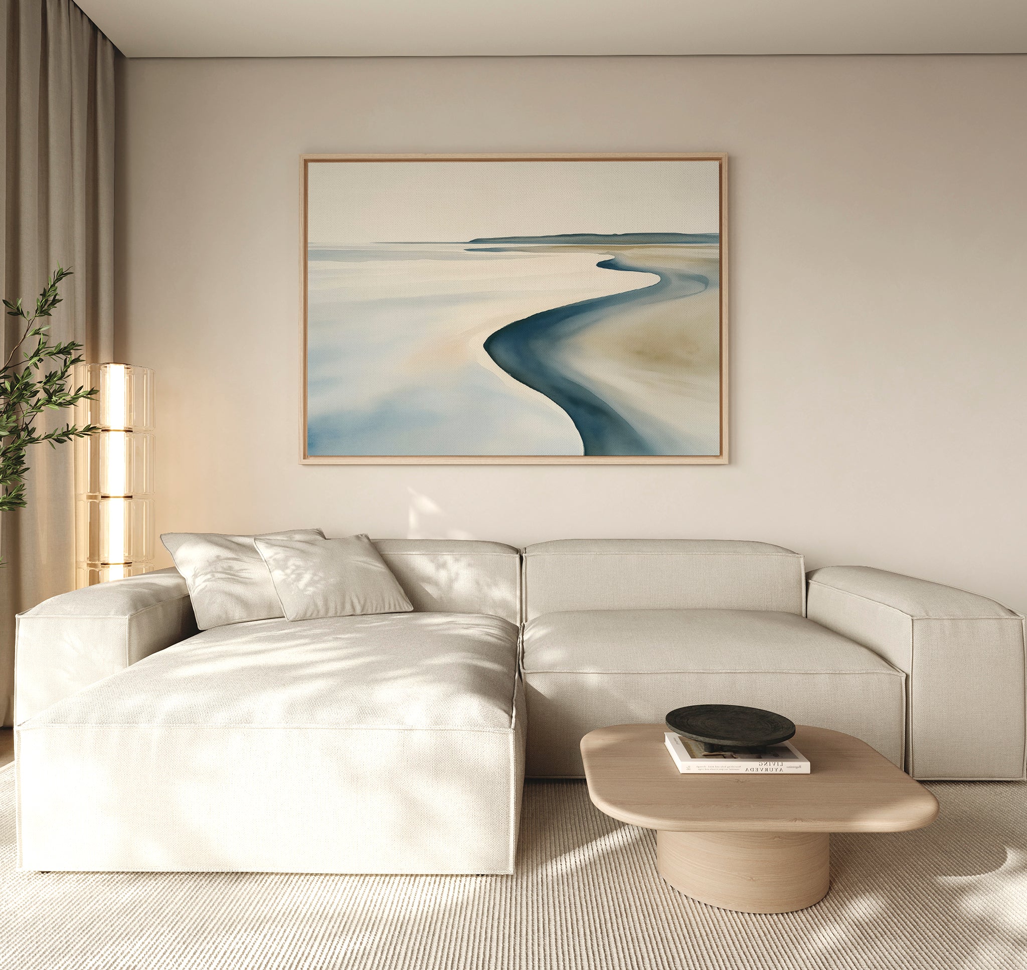 A modern living room features a light beige sectional sofa, low wooden coffee table, and the Serene Coastline Canvas Art – Horizontal, whose soft blue and sandy hues add to the calm, inviting atmosphere with minimalist neutral decor.