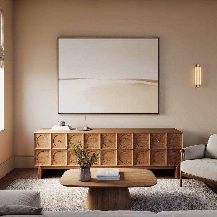 A minimalist living room with neutral tones featuring a light wood coffee table, geometric wood sideboard, beige sofa, Serene Expanse Canvas Art – Horizontal, a vase with branches, and soft natural light—perfect for modern decor.