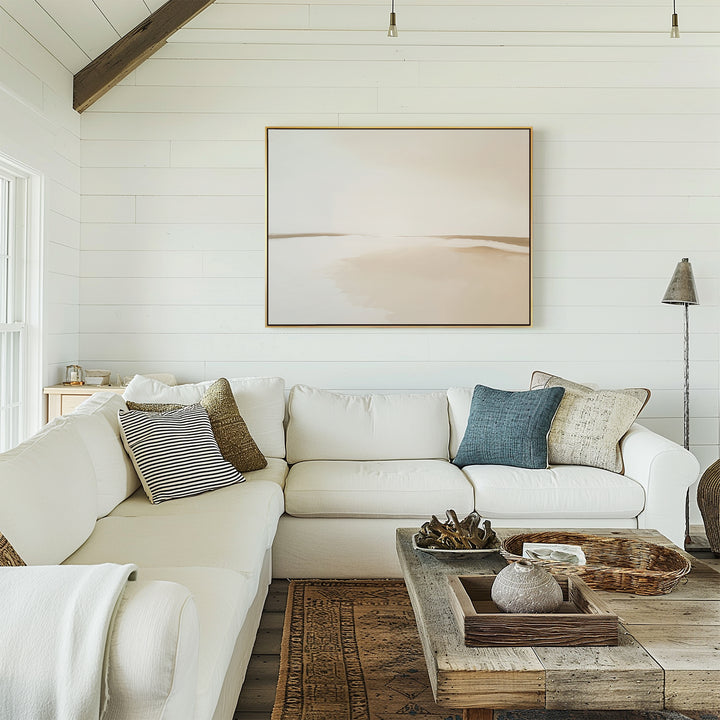 A bright living room with white shiplap walls, a large sectional sofa, assorted pillows, rustic wooden coffee table, decorative trays, and the Serene Expanse Canvas Art – Horizontal—ideal for lovers of modern, stylish living room decor.