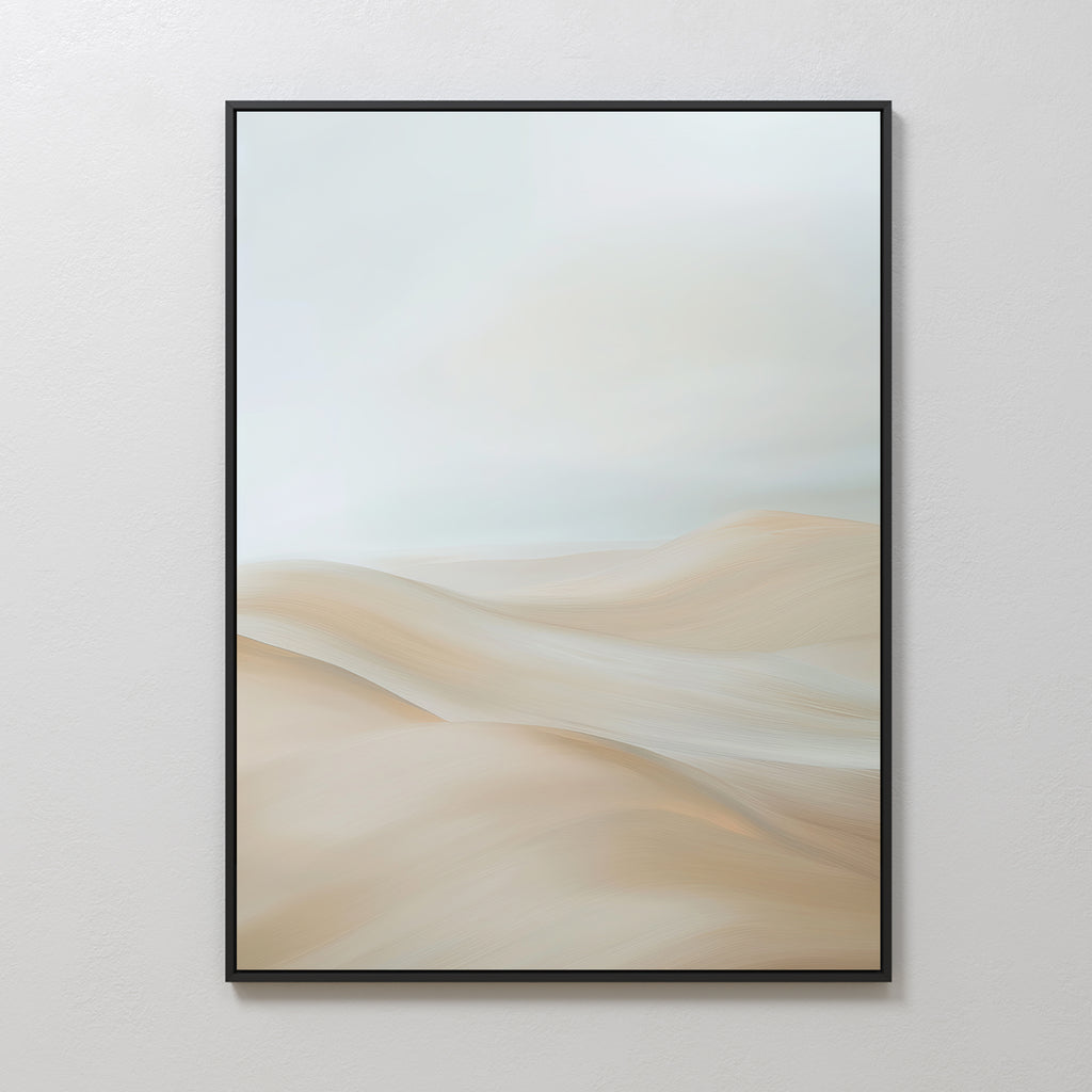 A framed Serene Peaks Abstract Canvas Art featuring soft, flowing sand dunes in beige and pale tones beneath a light, cloudy sky, displayed on a white wall.