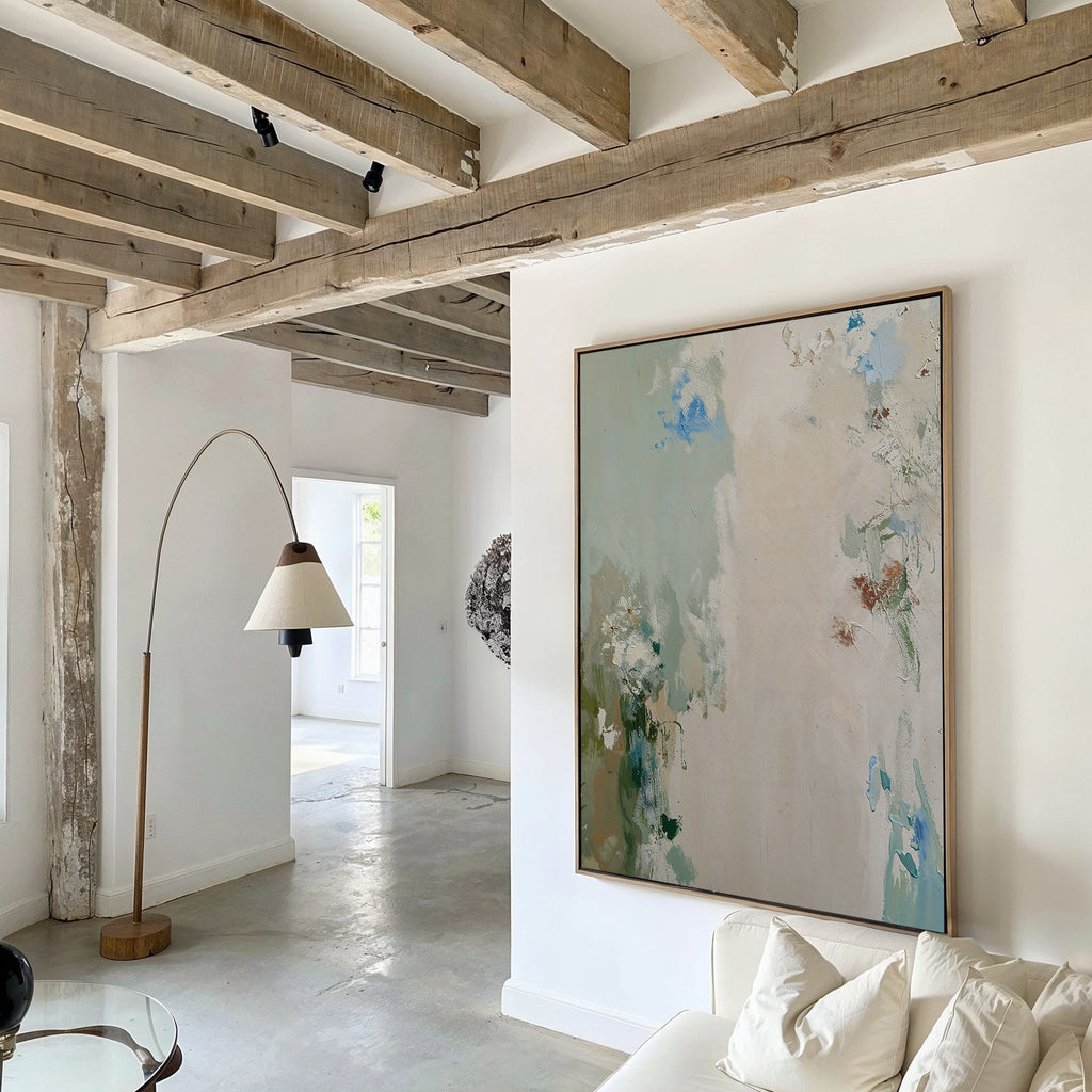 A bright, minimalist living room with exposed wooden ceiling beams, a curved floor lamp, a white sofa, and the Serenity Garden Abstract Canvas Art—yet the product description seems to lack important details.