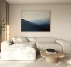 A modern living room with a beige sectional, light wood coffee table, minimal floor lamp, and the Shadowed Valley Canvas Art – Horizontal. Neutral tones and soft natural light create a serene, minimalist atmosphere.