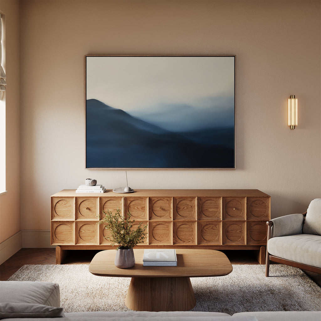 A modern living room features a light sofa, wooden coffee table, textured sideboard, and the Shadowed Valley Canvas Art – Horizontal. Soft lighting and neutral tones create a calm, inviting atmosphere.