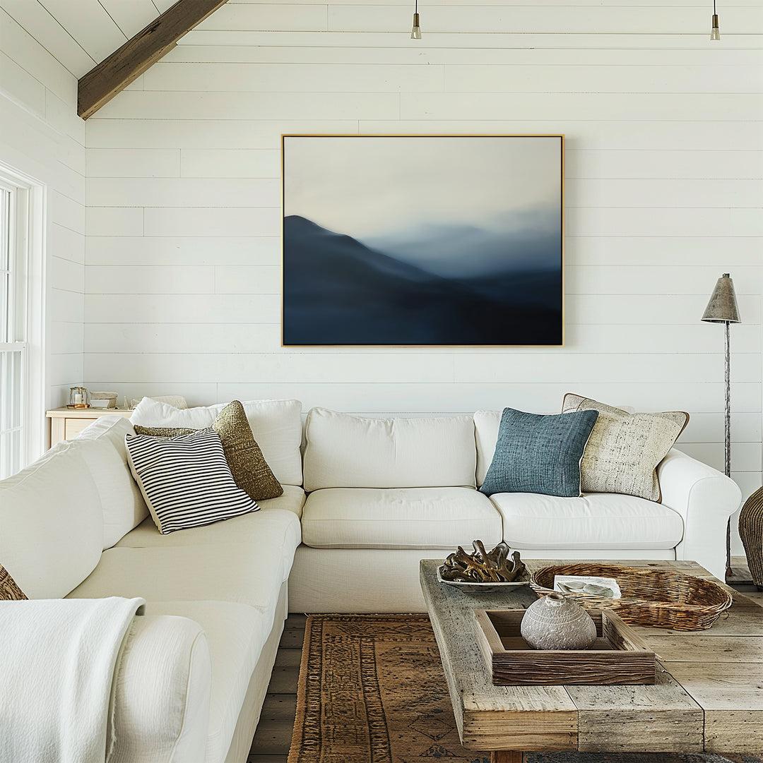 A bright, cozy living room with a white sectional sofa, mixed throw pillows, a rustic wood coffee table, and the Shadowed Valley Canvas Art – Horizontal hanging on a white shiplap wall. Natural light pours in through a side window.