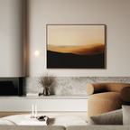 A modern living room with neutral tones features a brown curved sofa, a marble coffee table, and minimalist wall art—a framed Sienna Ridge Canvas Art abstract landscape—displayed above a low cabinet.