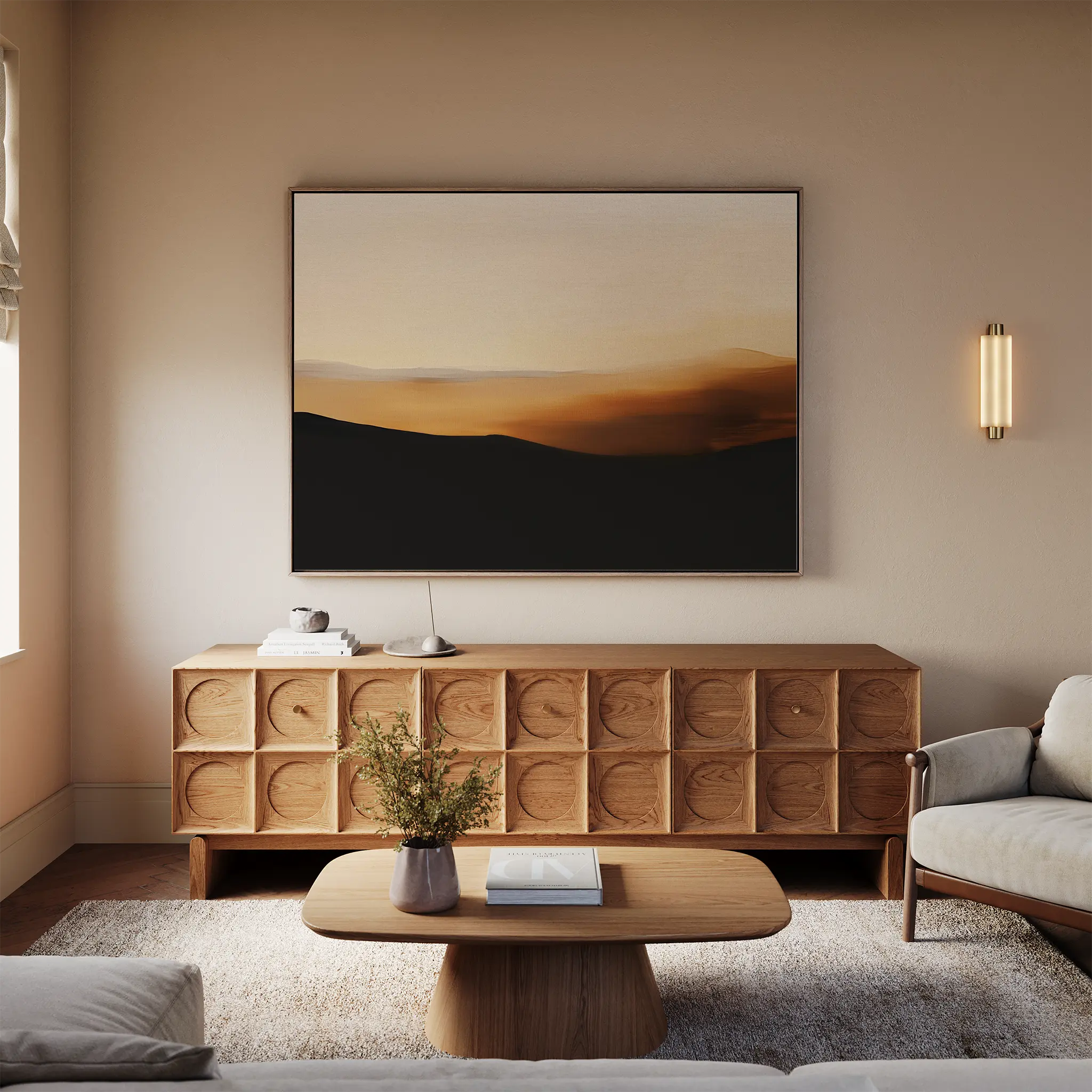 A modern living room features a light sofa, wooden coffee table, textured sideboard, and the Sienna Ridge Canvas Art above. A wall sconce, vase of flowers, and books complete the minimalist decor.