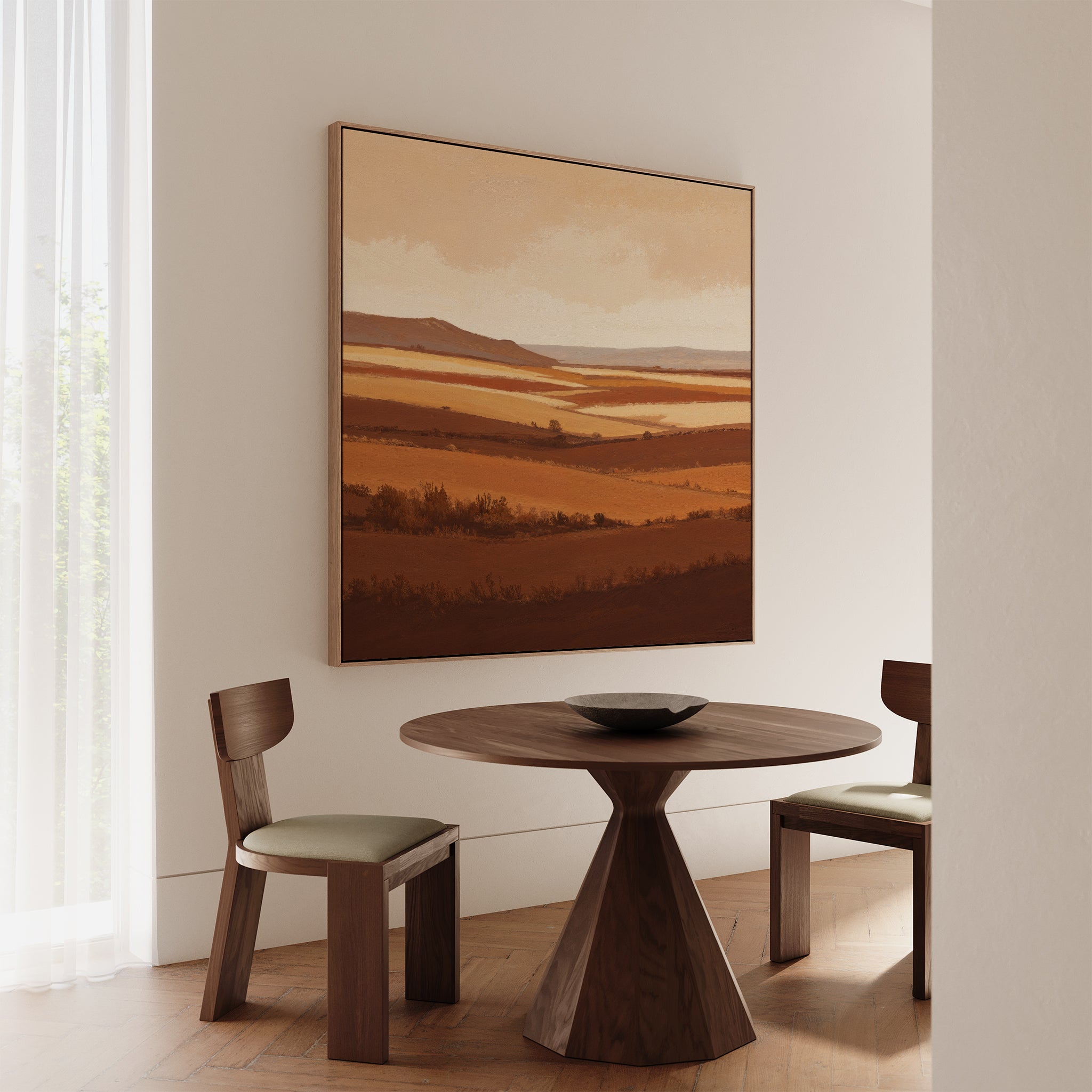 A minimalist dining area with a round wooden table, two cushioned chairs, and the Sienna Terrain Canvas Art evoking Nordic landscapes. Light filters through a sheer curtain, highlighting the space’s warm tones.