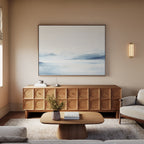 A modern living room in neutral tones features a geometric wooden sideboard, a coffee table with flowers, a light rug, plush sofa, and the Silent Glaciers Canvas Art as striking minimalist wall décor above the seating area.