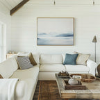 A cozy living room with white shiplap walls, a large white sectional sofa, assorted pillows, a rustic wooden coffee table with decor, and the Silent Glaciers Canvas Art hanging as minimalist wall art above the couch.