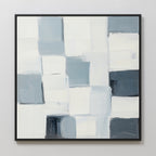 Silent Squares Abstract Canvas Art features a grid of overlapping white, grey, and blue rectangles, creating a textured geometric pattern. This minimalist wall art is framed in black and displayed on a light-colored wall.