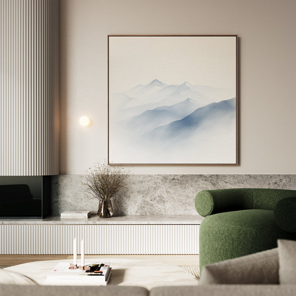 A modern living room with a green armchair, marble accents, a low table topped with books and candles, and Silent Summits Canvas Art—a minimalist mountain print—displayed above a vase of dried branches.