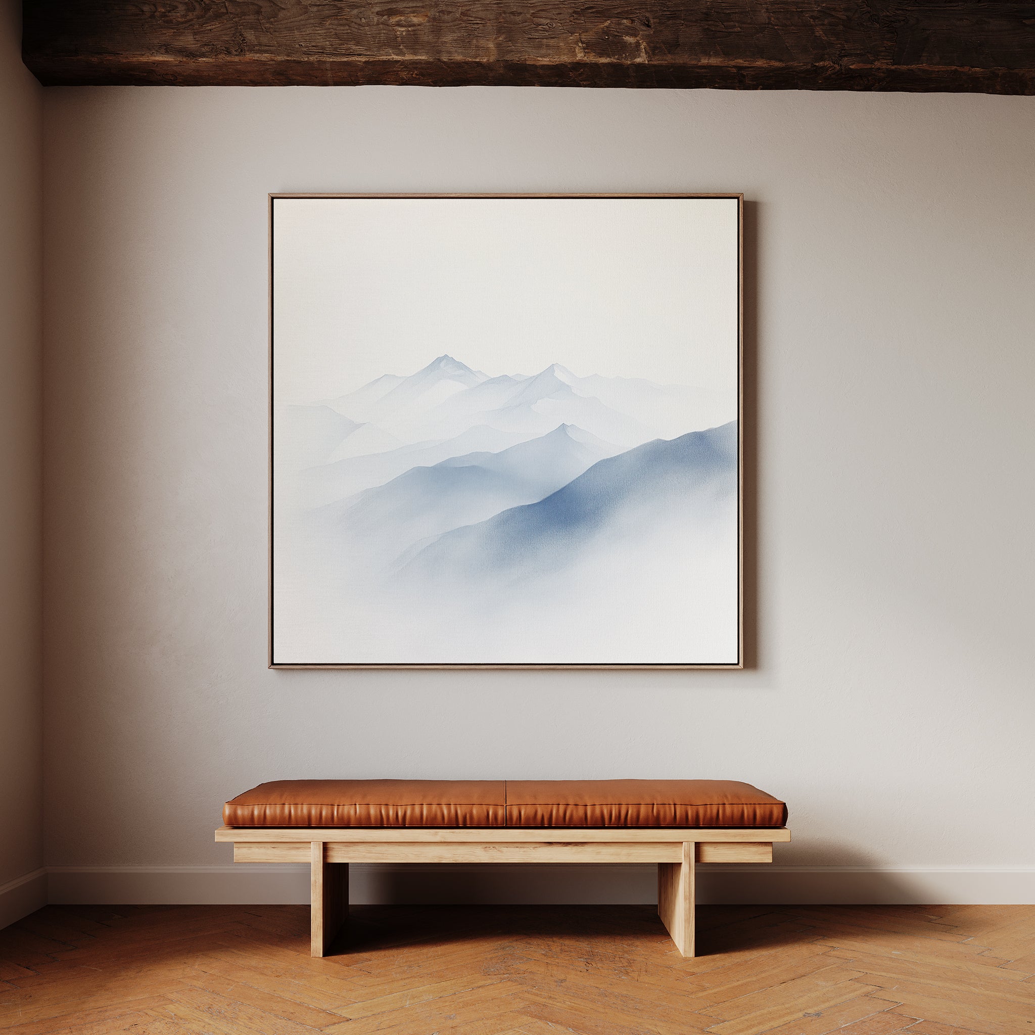 A minimalist room features a wooden bench with a brown leather cushion against a light wall. Above it hangs the Silent Summits Canvas Art—a framed painting of misty blue mountains—perfect for tranquil bedroom decor.