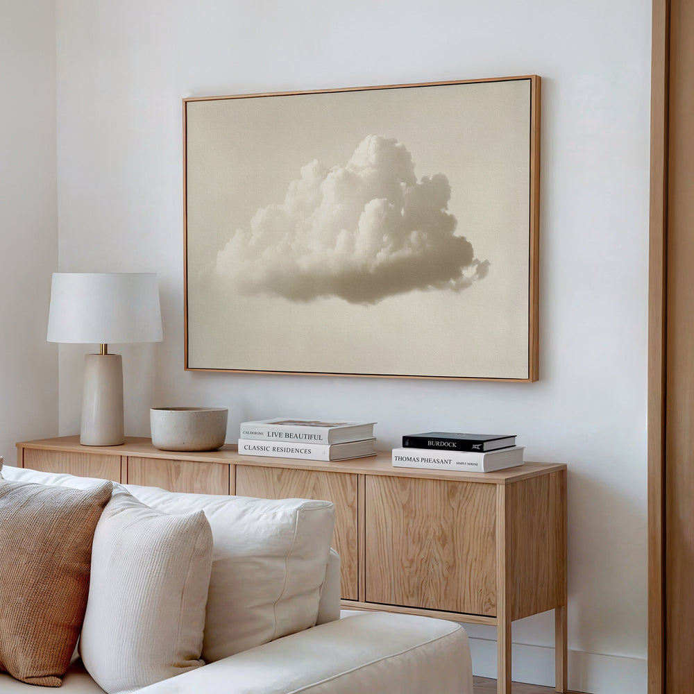 A modern living room features a light wood sideboard with stacked books, a lamp, bowl, and beige couch. Above the sideboard hangs the Singular Vapor Canvas Art – Horizontal, bringing minimalist style to the space.
