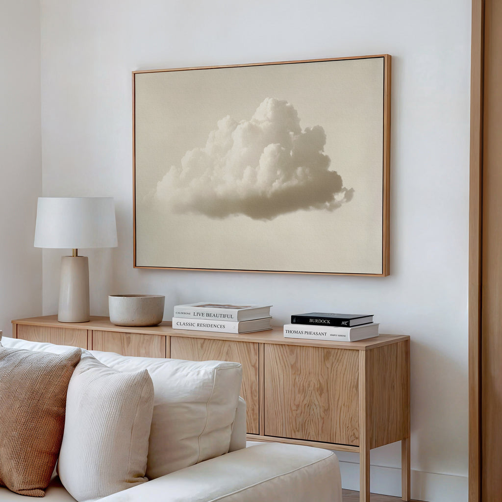A modern living room features a light wood sideboard with stacked books, a lamp, bowl, and beige couch. Above the sideboard hangs the Singular Vapor Canvas Art – Horizontal, bringing minimalist style to the space.