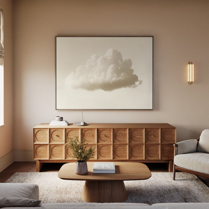 A minimalist living room with a wooden sideboard, the Singular Vapor Canvas Art – Horizontal above it, a round coffee table with a vase and book, a light-colored sofa, and soft lighting against beige walls.