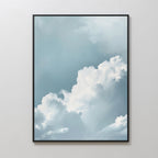 Sky Serenade Abstract Canvas Art, featuring fluffy white clouds on a light blue sky, adds a serene and minimalist touch to any living room decor when displayed on a plain white wall.