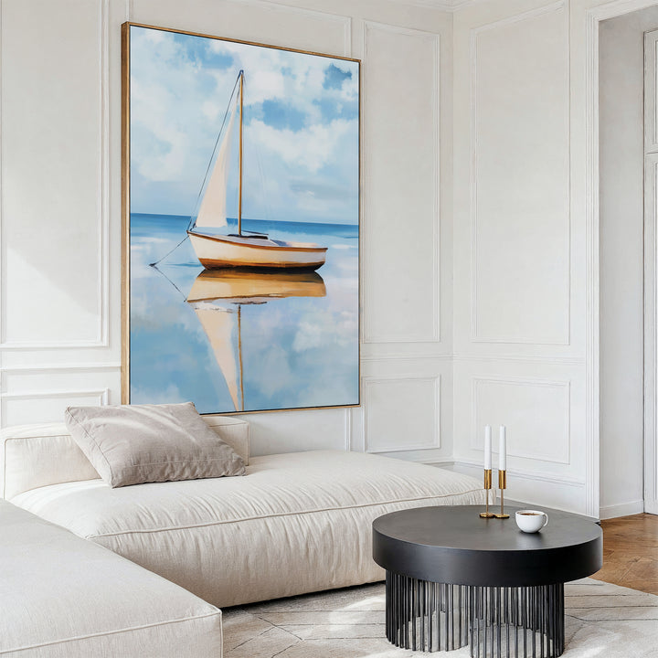 A modern living room featuring a white sectional sofa, round black coffee table, and the Skybound Reflection Canvas Art—a minimalist sailboat painting on calm blue water—perfect for stylish, contemporary wall decor.