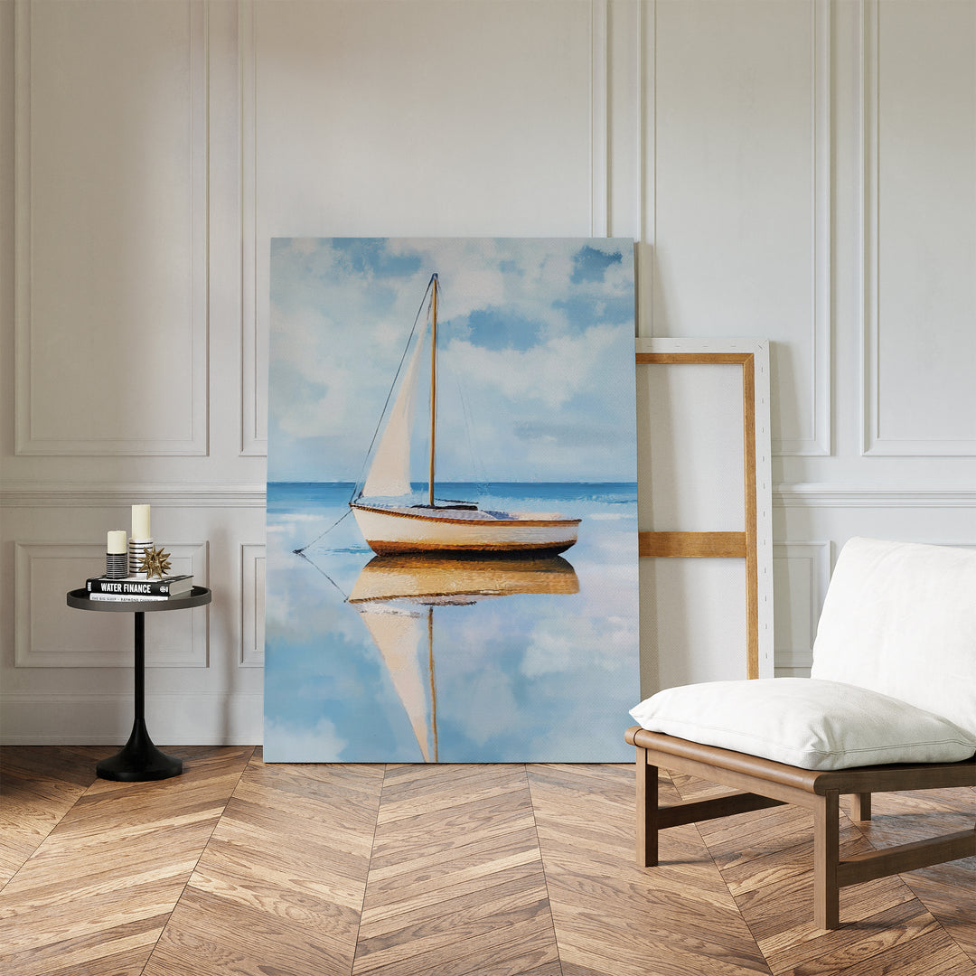 The Skybound Reflection Canvas Art, featuring a sailboat on calm water in minimalist style, leans against a white paneled wall in a tranquil room with herringbone floors, a cushioned chair, and a round table with candles.