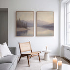 A minimalist living room with a woven chair, white side table, and three lit candles. Above, sunlight illuminates the Smoky Peaks Set of 2 landscape wall art, which hangs near a tall window on the right.