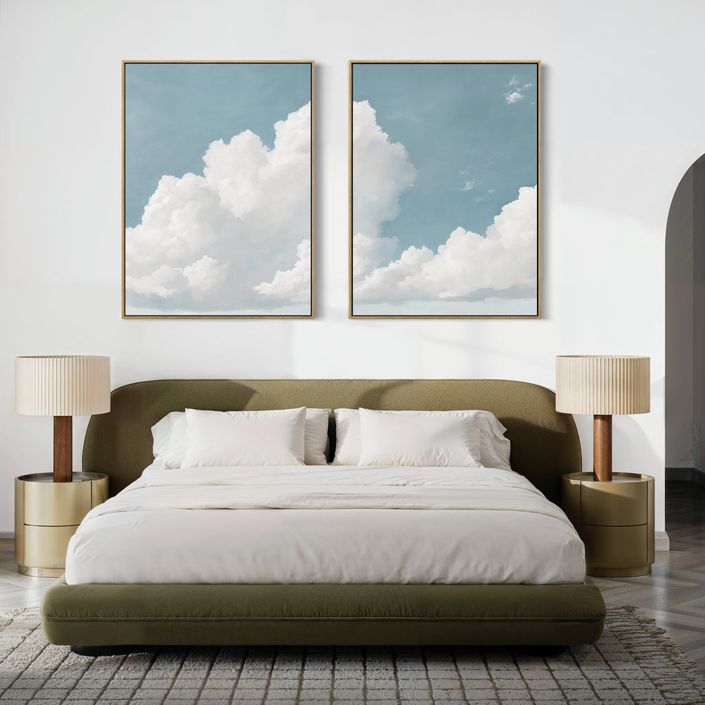 A modern bedroom with an olive green bed, white bedding, and beige nightstands features the Soaring Peace Set of 2 cloud prints above the bed, bringing a tranquil and cozy touch to the minimalist space.
