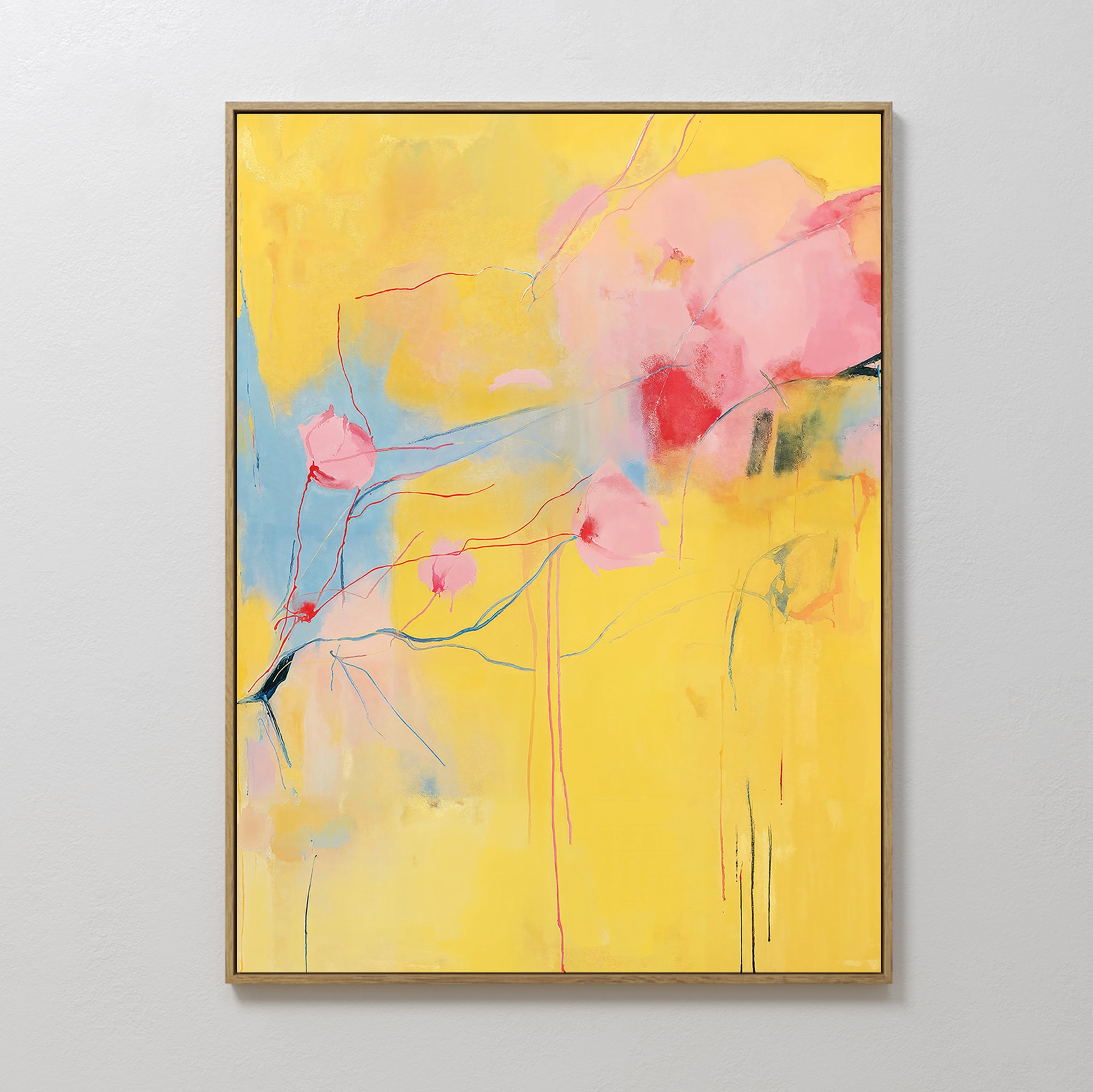 Soft Bloom Abstract Canvas Art features a yellow background with soft pink and blue floral-inspired shapes, framed in gold and displayed on a white wall—ideal as vibrant wall art for your living room decor.