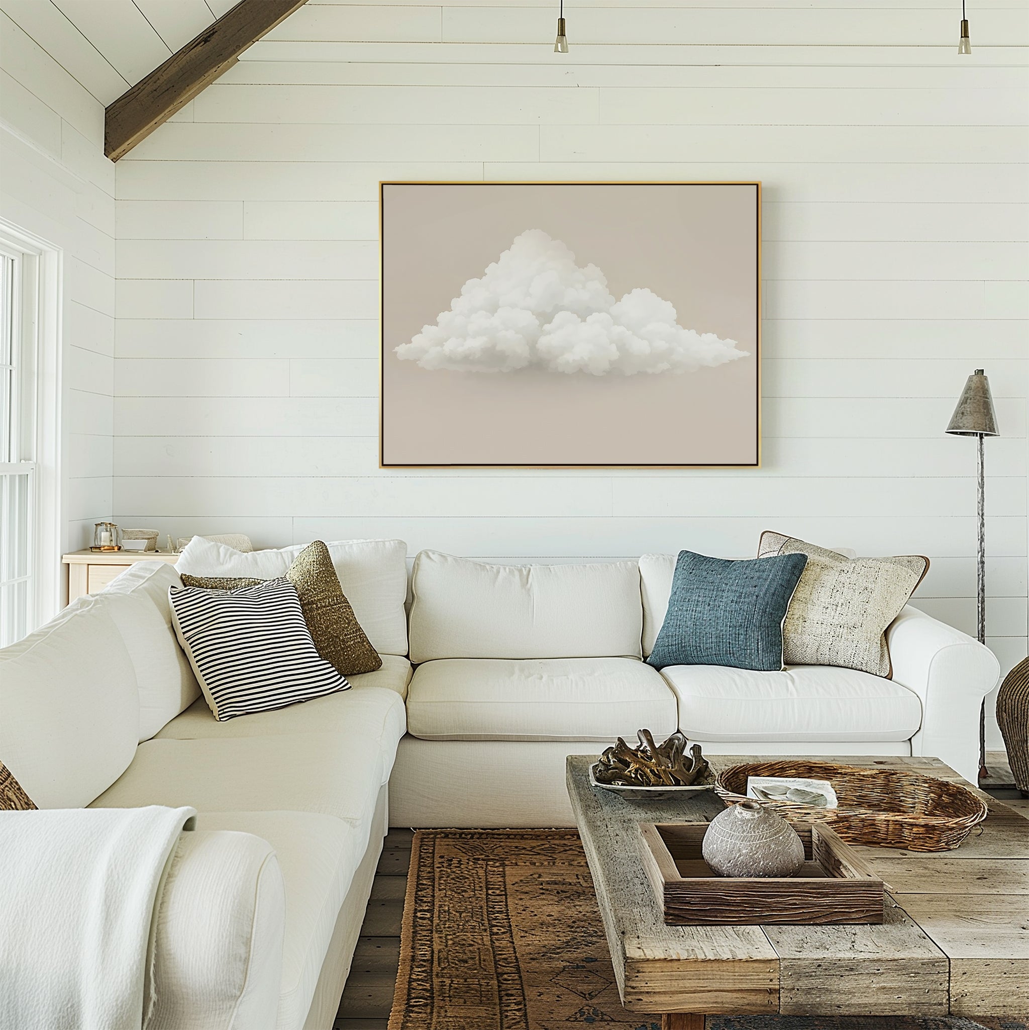 A cozy living room with a white sectional sofa, assorted cushions, a rustic wooden coffee table, and the Soft Drift Canvas Art featuring clouds above the couch. White shiplap walls and natural light highlight calming neutral tones.