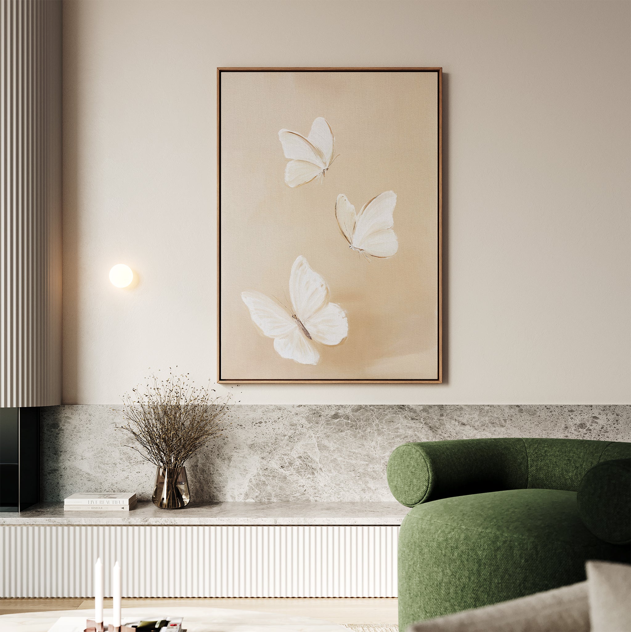 A minimalist living room features elegant wall decor—a Linen Wings Canvas Art of three white butterflies above a marble shelf, paired with a green curved sofa and a vase of dried flowers for a serene look.