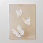 Linen Wings Canvas Art features three white butterflies with delicate wings on a light beige background. Spaced apart at various angles, this elegant piece adds gentle movement and charm to your wall decor.