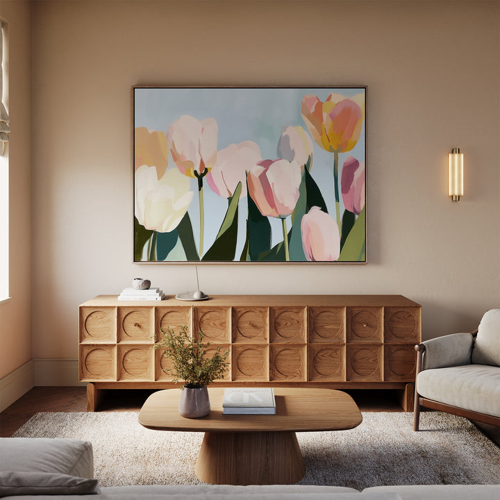 A cozy living room features a light sofa, wooden coffee table, and sideboard. Above the sideboard hangs the Soft Field Canvas Art, while a small vase of flowers brings charm to the table.