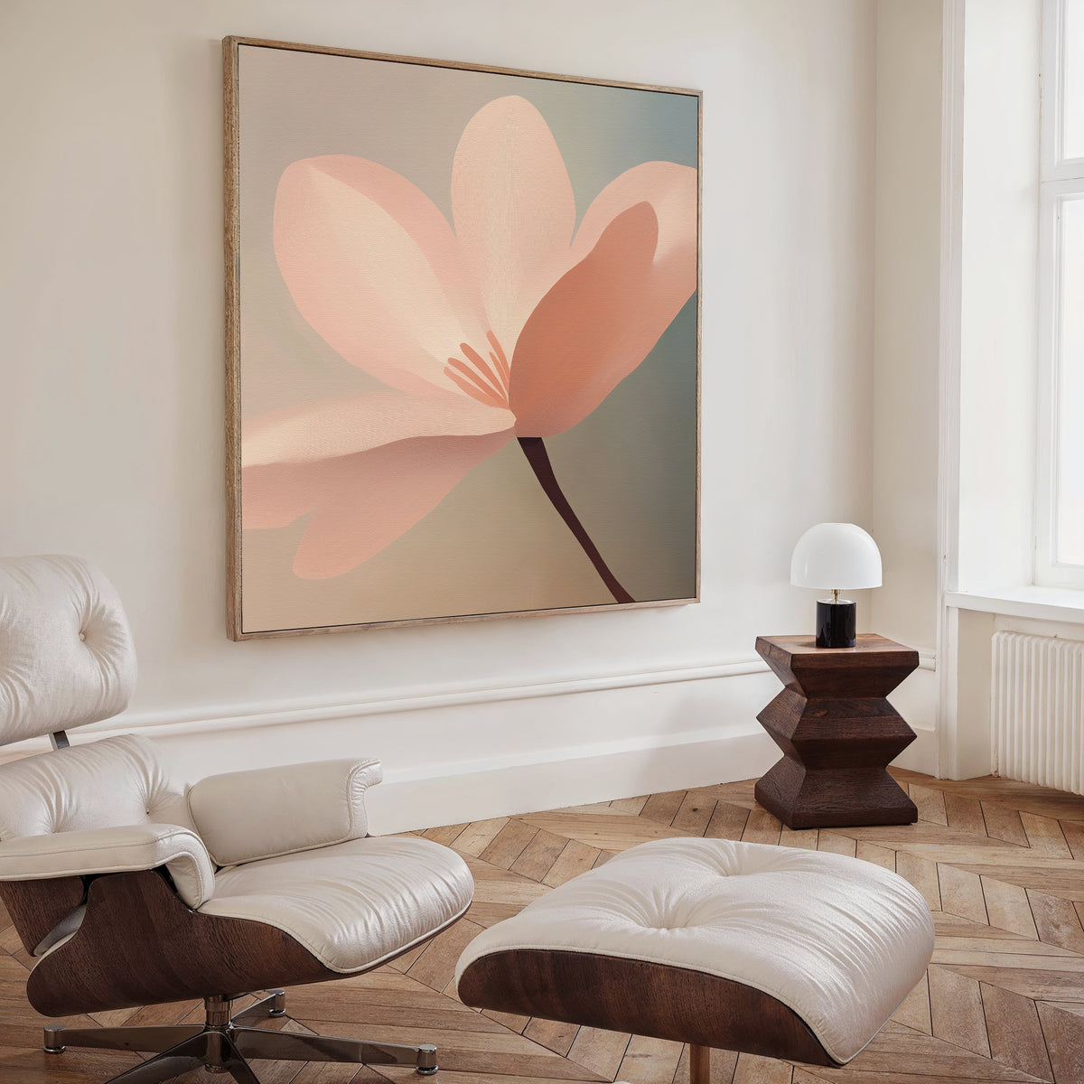 A modern living room features Soft Pink Glow Canvas Art, a white leather lounge chair and ottoman, a dark wood side table, and a small lamp with a white shade. Sunlight from tall windows highlights the elegant decor.