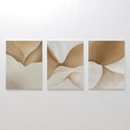 The Soft Sands Set of 3 features abstract canvases with flowing shapes in beige, tan, and cream tones, displayed side by side. This minimalist wall art brings a calming ambiance with its organic forms and neutral palette.