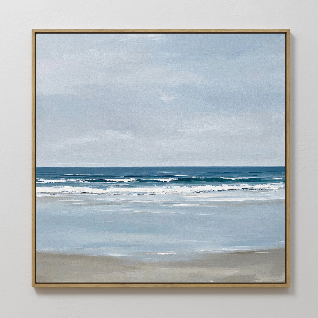 The Soft Tide Canvas Art features a serene beach scene with gentle waves and a calm sea in soft blue, white, and beige tones, making it the perfect coastal decor for any white wall.