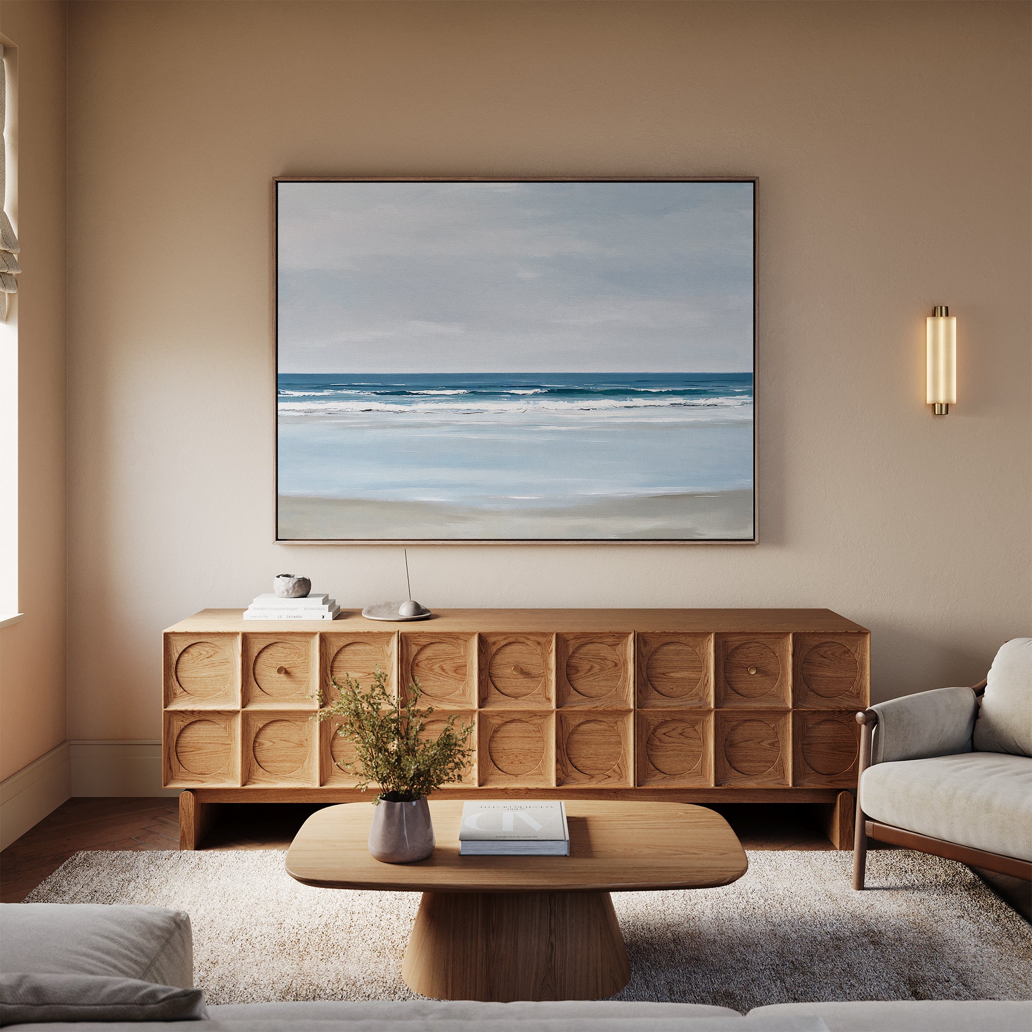 A minimalist living room featuring a light wood sideboard, beige sofa, small wooden coffee table with a vase, and the Soft Tide Canvas Art – Horizontal hanging in a large frame above the sideboard.